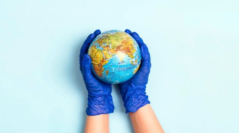 Two hands wearing blue disposable medical gloves cradle a globe, with Africa, Europe, and Asia visible.
